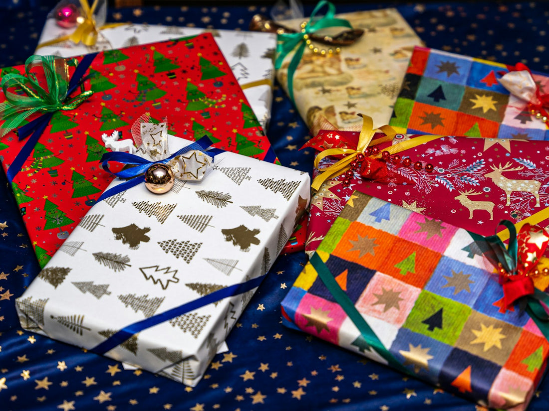 A pile of colorful wrapped holiday presents with ribbons and bows