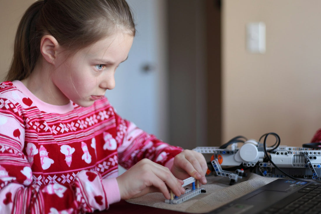 Young girl concentrating while building a robot construction kit